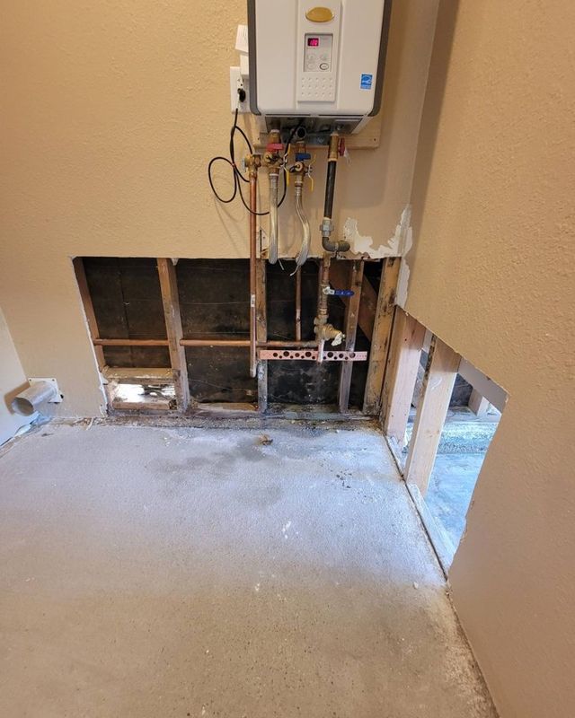 Water heater closet with leak-damaged drywall cut out down to the studs